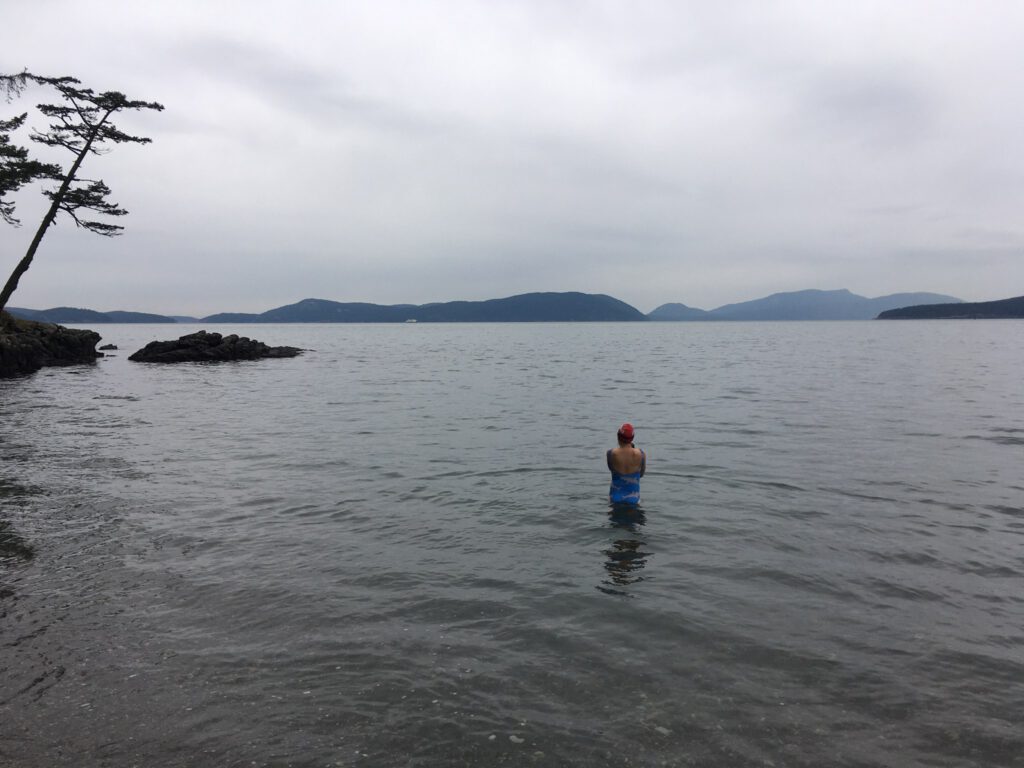 Female swimmer wading into cold waters